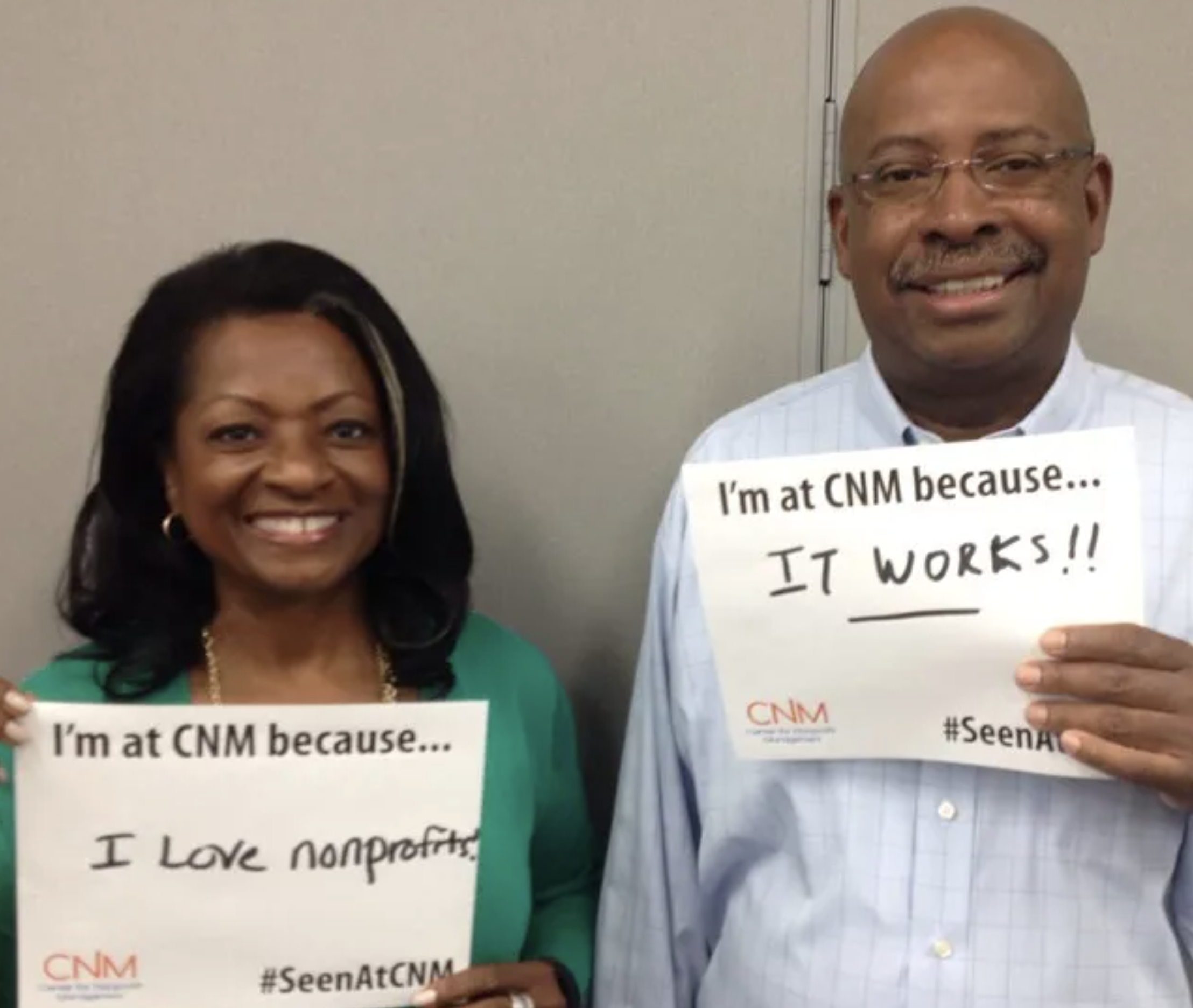 2 nonprofit employees posing holding the sings " I am at CNM because I love nonprofit" and "I am at CNM because it works"